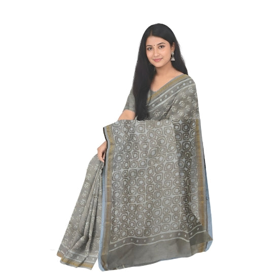 A woman modeling a gray saree with a geometric block print pattern and a gold border, set against a plain white background.