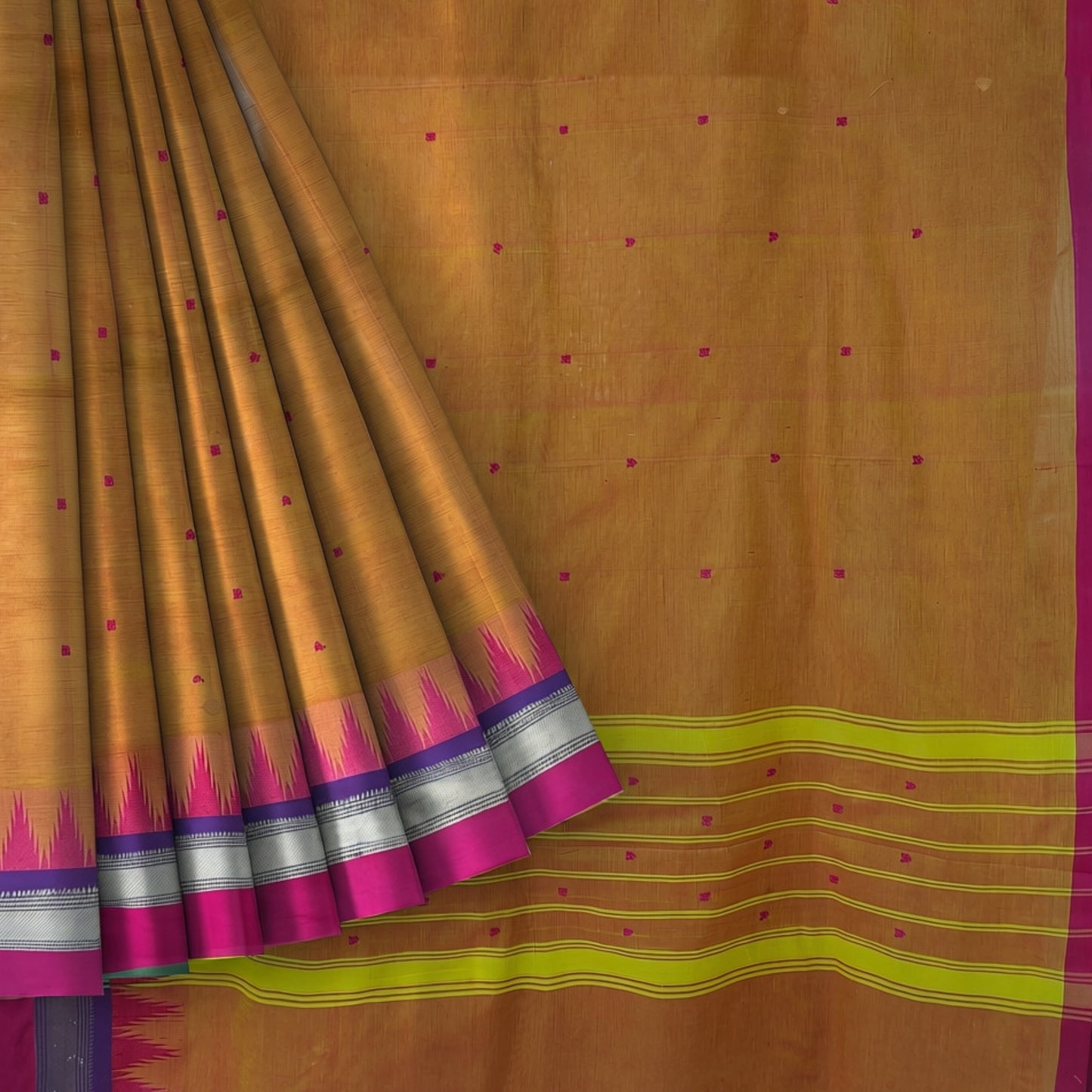 A golden-brown silk saree with a magenta border, a yellow-green and purple ikat border, and small magenta dot motifs scattered across the body.