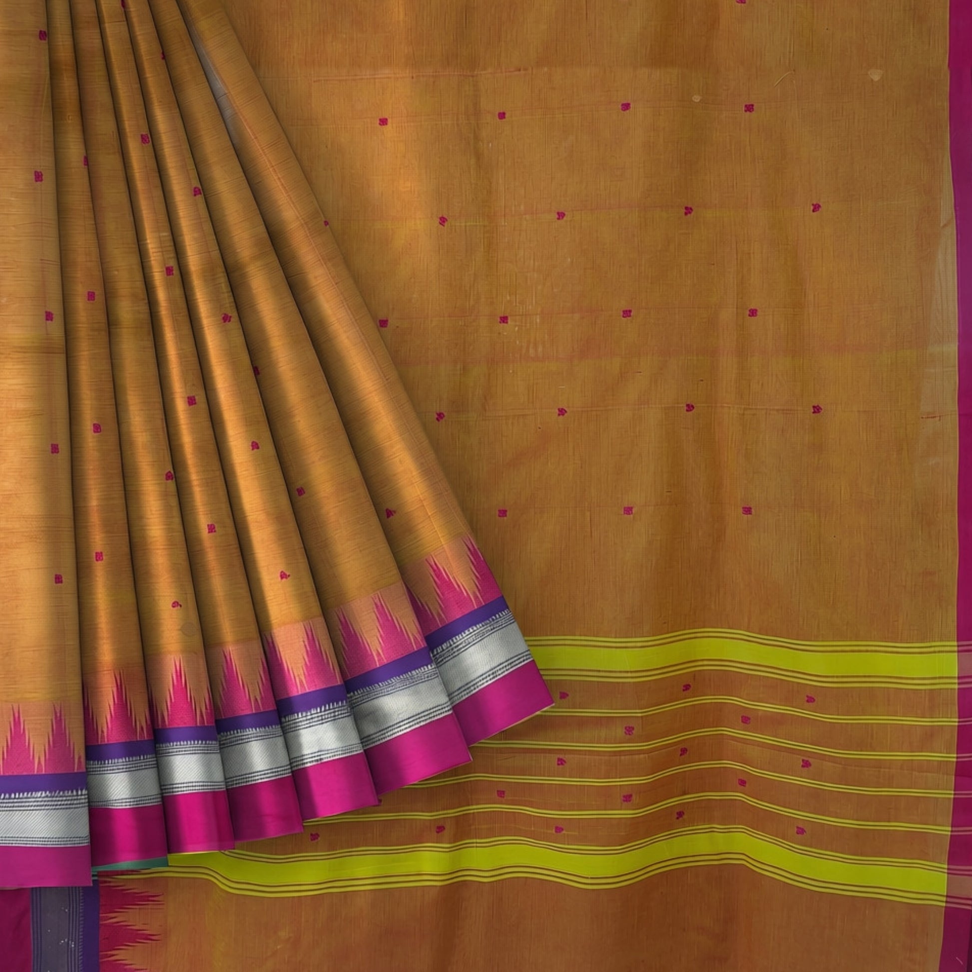 A golden-brown silk saree with a magenta border, a yellow-green and purple ikat border, and small magenta dot motifs scattered across the body.